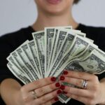 O femeie ținând bancnote de dolari, simbolizând prosperitatea în vis.