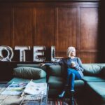 O femeie relaxându-se pe o canapea într-un hotel, cu o cafea în mână.