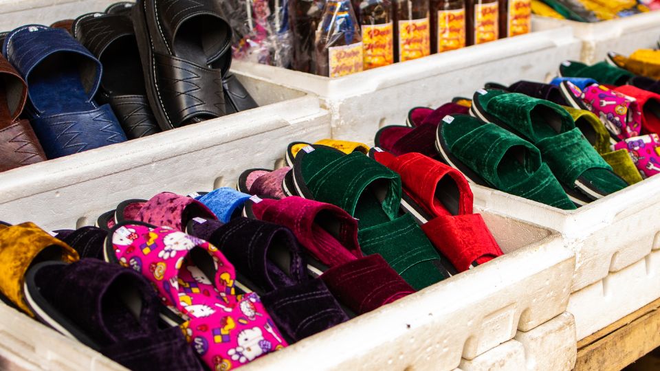 Papuci colorati expuși pe un stand, variind de la negru la nuanțe vibrante.