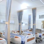 Interiorul unui spital cu paturi și perdele pentru intimitate.