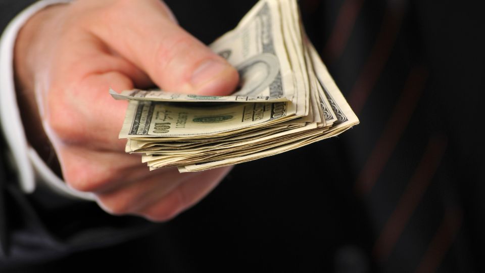 Un bărbat oferă bani, simbolizând oportunități financiare și schimburi.