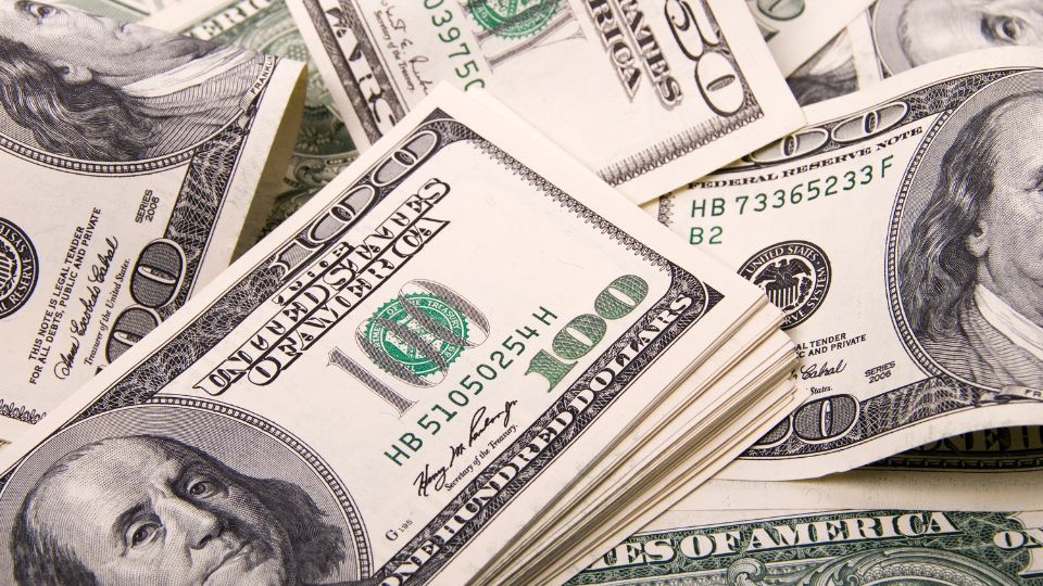 Bancnote de 100 dolari americani aranjate pe o masă, simbolizând prosperitate și succes.